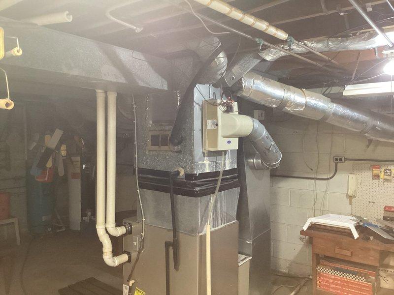 Conducted on-site evaluation for air conditioning replacement options at residential property. Inspected existing HVAC system located in basement mechanical room, including furnace unit with metallic ductwork configuration and associated utility infrastructure. Assessed current equipment condition, ductwork layout, electrical connections, and available space for potential system upgrades. Documented existing installation with photographs showing furnace placement, PVC condensate lines, electrical panel access, and mechanical room configuration. Reviewed water heater and expansion tank positioning to determine clearance requirements for new AC equipment installation. Provided comprehensive replacement options and recommendations based on existing infrastructure and mechanical room layout.