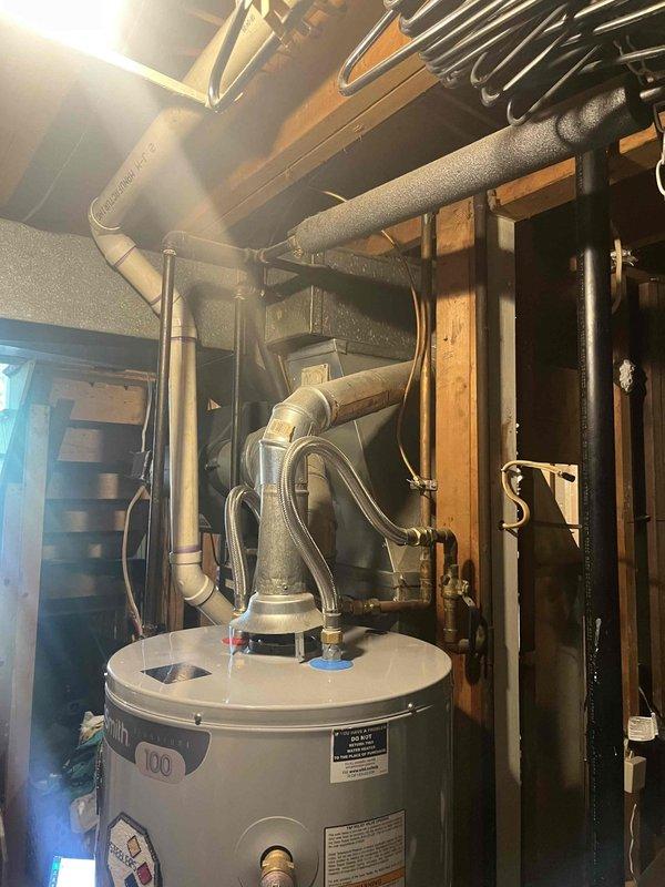 Completed HVAC system assessment for non-operational gas furnace and failed air conditioning system in residential basement utility area. Documented existing ductwork configuration, plumbing connections, and mechanical equipment layout including water heater integration points to prepare comprehensive replacement estimate for new heating and cooling system installation.