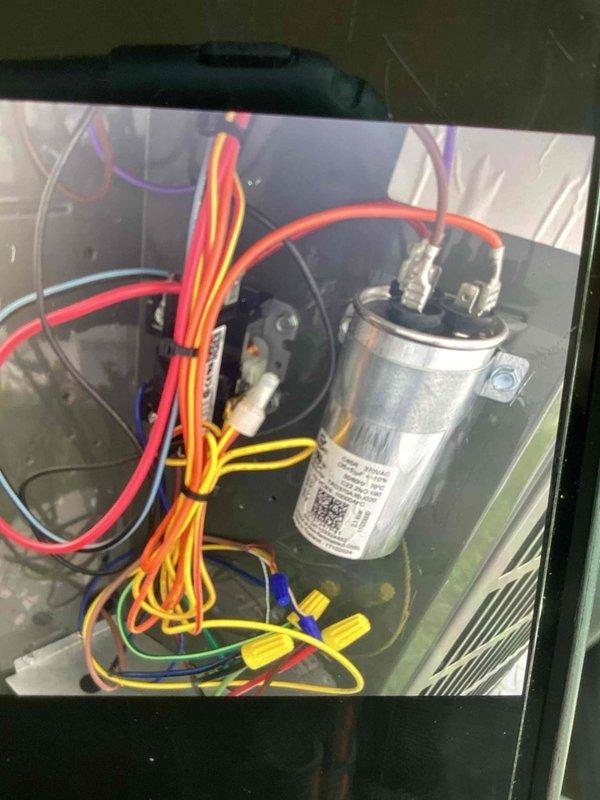 Responded to no cooling call on recently installed system experiencing clicking sounds and yellow indicator lights. Upon inspection, opened condensing unit access panel and documented electrical connections and capacitor installation. Verified proper wire routing, wire nut connections, and capacitor mounting within the unit's electrical compartment.