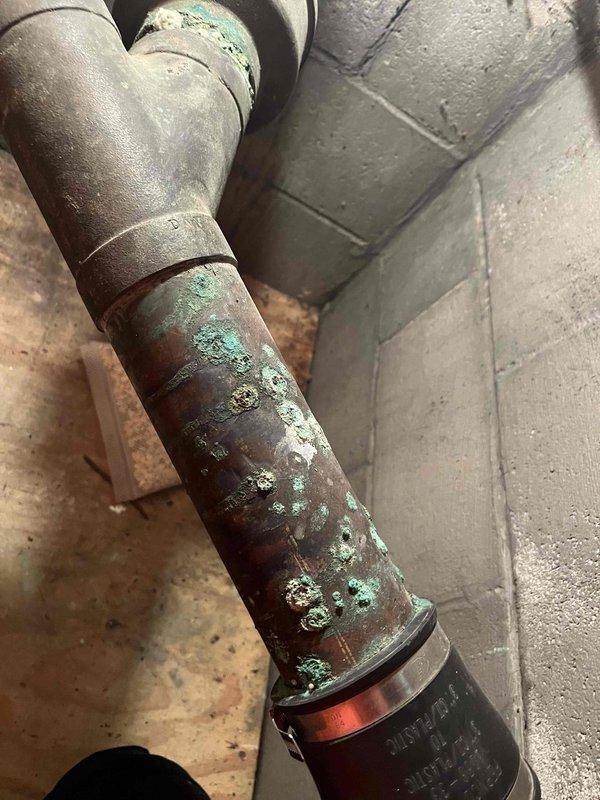 Responded to emergency service call for pipe burst with water supply shut off. Conducted comprehensive assessment of damaged plumbing system to prepare insurance claim estimate. 

Inspected corroded copper piping in basement utility area showing extensive green patina (verdigris) and oxidation damage throughout multiple sections. Documented deteriorated pipe assembly including galvanized steel elbow fitting, metal coupling bands, and connection points exhibiting significant age-related degradation from prolonged moisture exposure. Evaluated structural integrity of affected copper lines and adjacent plumbing components.

Assessed bathroom vanity area where demolition work exposed wall cavity and plumbing infrastructure. Examined white PVC drain lines, red and blue PEX supply tubing, and gray piping running through wall studs. Documented existing plumbing configuration and water damage extent for estimate preparation. Photographed all affected areas including exposed framing, pipe routin
