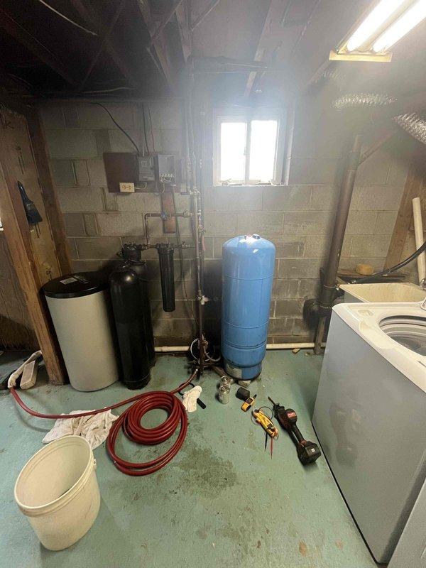 Completed water heater replacement in basement of older residential property. Existing water heating system was removed and new unit installed, integrated with existing plumbing infrastructure including water softener, filtration system, and pressure tank. All copper pipe connections, valves, and fittings were properly configured to ensure seamless operation with the home's water treatment equipment.