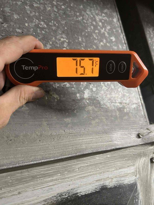 Responded to no cooling call at vacant property for 2009 Goodman system. Upon arrival, verified ambient temperature reading of 75.1°F and inspected outdoor condensing unit. Observed refrigerant lines, brass service valves, and system components showing age-related wear consistent with 10+ year old equipment, with service port tape indicating previous refrigerant work.