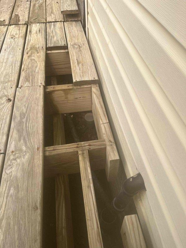 Responded to service call for suspected sump pump discharge pipe leak. Upon inspection, accessed the discharge line routing through exterior deck structure and attic space. Confirmed active leak at pipe penetration point where discharge line exits through building envelope. Removed deck boards to expose compromised pipe connection and traced discharge line through attic to identify full extent of water intrusion. Documented deteriorated pipe seal and improper weatherproofing at roof/ceiling penetration point causing moisture infiltration. Recommended replacement of damaged discharge pipe section, proper sealing of deck penetration, and installation of appropriate flashing and weatherproofing at attic penetration to prevent future leaks and water damage.