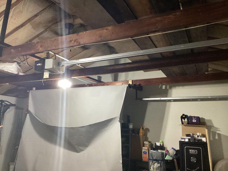 Conducted site assessment for ductless mini-split installation at residential property with no existing AC equipment. Evaluated exterior mounting location adjacent to building foundation and interior garage/basement area with exposed ceiling joists to determine optimal placement for outdoor condenser unit and indoor air handler, documenting conditions and measuring spaces for equipment specifications and refrigerant line routing.