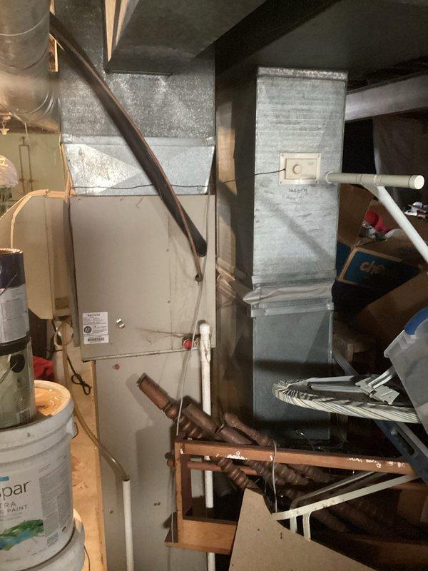 Conducted comprehensive assessment of existing residential HVAC system in basement mechanical room. Evaluated beige furnace unit with copper refrigerant lines and associated ductwork for replacement needs. Inspected wall-mounted programmable thermostat with exposed internal components, including circuit board, wiring connections, and battery compartment. Documented current system configuration including air handler, metal ductwork, and refrigerant line routing. Prepared detailed estimate for complete air conditioning system replacement based on equipment age, condition, and operational deficiencies identified during inspection.
