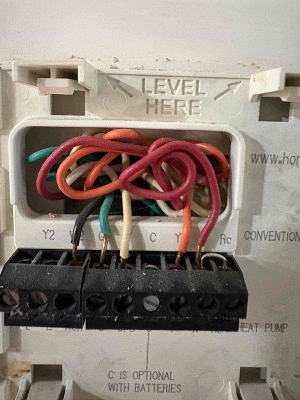 Conducted on-site evaluation for air conditioning system replacement. Assessed existing thermostat wiring configuration, documenting multi-stage heat pump setup with Y, Y2, G, C, and Rc connections at wall-mounted base plate. Inspected exterior electrical disconnect and line set penetration point on building exterior, verifying conduit routing and junction box placement. Provided customer with equipment replacement options and system upgrade recommendations based on current installation configuration.