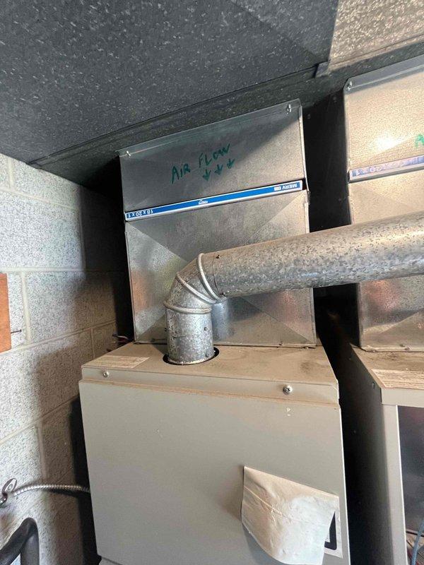 Conducted site assessment at church facility to evaluate failed HVAC unit and provide replacement estimate. One of two existing units experienced complete system failure requiring full replacement. Inspected mechanical room installation, documented existing ductwork configuration including air handler with directional airflow markings, galvanized metal duct connections, and equipment housing mounted against concrete block walls. Photographed current system layout showing elbow duct connectors, flexible ductwork routing, and equipment positioning to determine proper sizing and installation requirements for replacement unit.