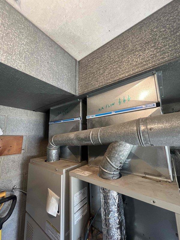 Conducted site assessment at church facility to evaluate failed HVAC unit and provide replacement estimate. One of two existing units experienced complete system failure requiring full replacement. Inspected mechanical room installation, documented existing ductwork configuration including air handler with directional airflow markings, galvanized metal duct connections, and equipment housing mounted against concrete block walls. Photographed current system layout showing elbow duct connectors, flexible ductwork routing, and equipment positioning to determine proper sizing and installation requirements for replacement unit.