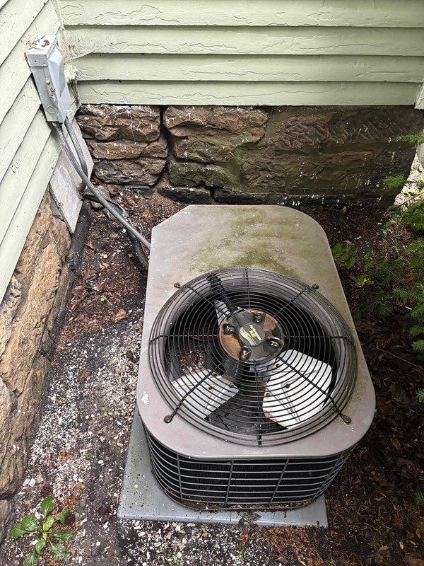 Conducted replacement estimate for residential HVAC system with 25-year-old Lennox furnace located in basement and matching-age outdoor air conditioning condenser unit. Both systems have exceeded their typical service life expectancy and are candidates for complete replacement with modern, energy-efficient equipment. Documented existing equipment conditions through photographs showing outdoor condenser unit on concrete pad with weathered foundation surroundings and basement furnace installation with current ductwork, refrigerant lines, and PVC venting configuration.