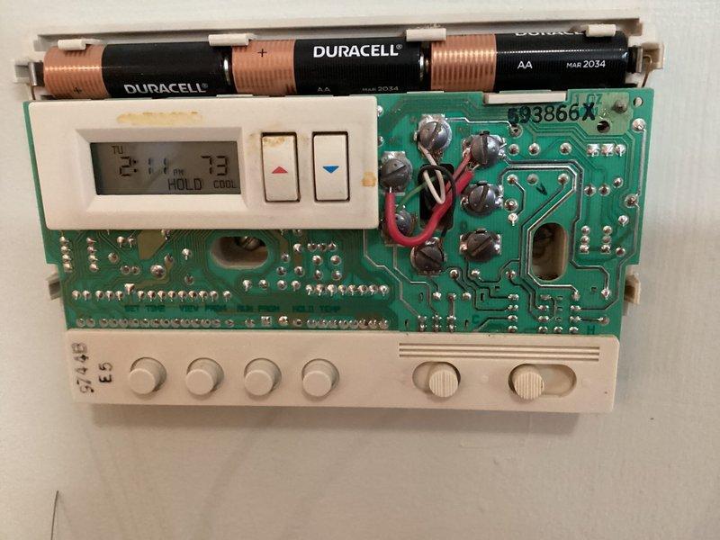 Conducted HVAC equipment assessment for replacement estimate on 29-year-old furnace and air conditioning system. Both units confirmed operational at time of inspection. Evaluated existing programmable thermostat functionality, documenting internal components including circuit board condition, battery compartment, and control interface displaying proper temperature readings and system status indicators.