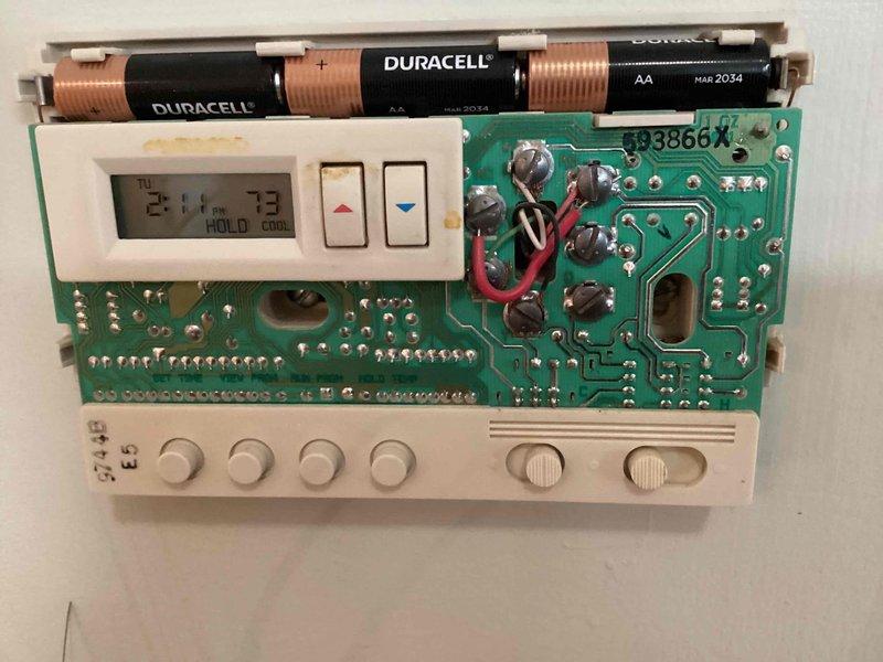 Conducted HVAC equipment assessment for replacement estimate on 29-year-old furnace and air conditioning system. Both units confirmed operational at time of inspection. Evaluated existing programmable thermostat functionality, documenting internal components including circuit board condition, battery compartment, and control interface displaying proper temperature readings and system status indicators.