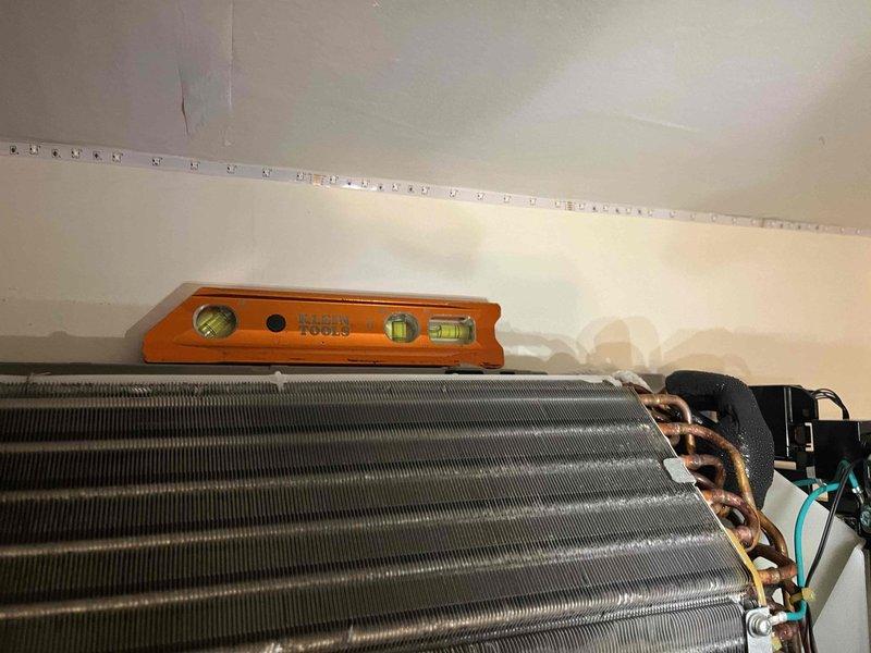 Responded to callback for mini split air handler leaking onto floor. Inspected evaporator coil assembly and refrigerant line connections for source of water discharge. Verified proper leveling of indoor unit using torpedo level to ensure adequate condensate drainage pitch. Checked copper line set connections and associated fittings for refrigerant leaks or improper insulation that could cause condensation issues. Documented equipment condition and installation positioning with photographs for service records.