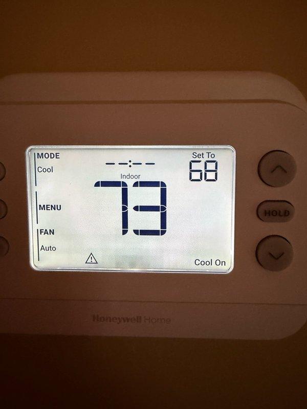 Responded to callback for system not cooling properly. Upon arrival, found Honeywell Home thermostat displaying alert status with warning indicator. Current indoor temperature reading 73°F with setpoint at 68°F, system calling for cooling but failing to achieve desired temperature. Investigated thermostat alert condition and addressed communication or sensor issue preventing proper system operation. Cleared alert status, verified thermostat functionality, and confirmed proper system response to cooling demand. Documented conditions with photos for service records.