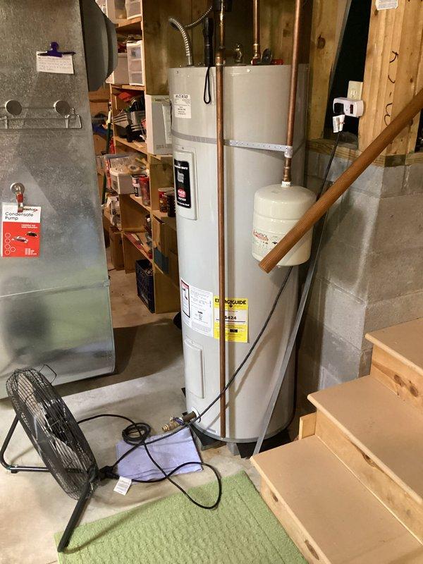 Performed assessment of existing 50-gallon electric water heater in basement utility area. Customer requested conversion from electric to gas water heater system. Documented current installation including copper supply lines, expansion tank, electrical connections, and surrounding plumbing infrastructure. Photographed existing equipment and utility space configuration to prepare for future gas water heater installation and necessary modifications to accommodate gas supply line, venting requirements, and updated connections.