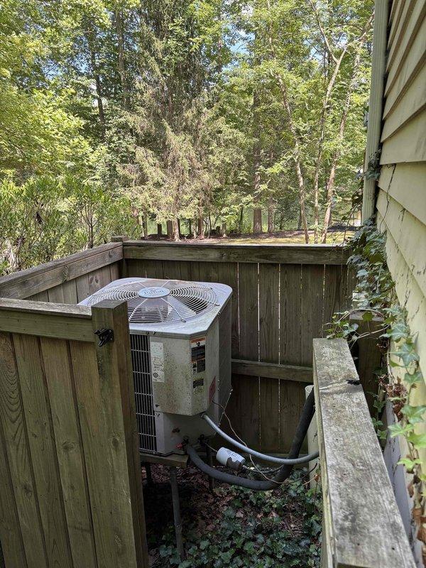 Conducted on-site evaluation for complete HVAC system replacement in all-electric residential property. Assessed existing 23-year-old heat pump condensing unit located exterior against privacy fence and 23-year-old air handler installed in basement. Unit showed weathering and discoloration on exterior casing, with compressor previously replaced in 2014. Documented current equipment condition through photographic survey, including refrigerant line routing and installation clearances. Provided comprehensive replacement estimate for new heat pump and air handler system to modernize climate control equipment.