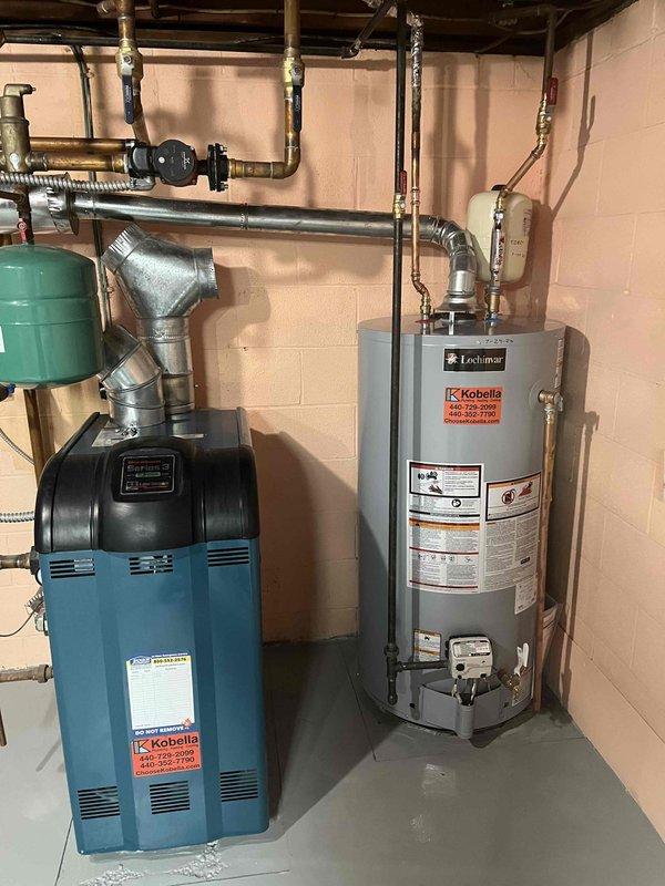 Completed annual maintenance on a 50-gallon lowboy natural gas water heater. Inspected burner assembly and confirmed proper combustion with visible blue flame through viewing port, indicating efficient gas-to-air mixture. Verified all plumbing connections, copper piping, shut-off valves, and associated equipment including water treatment system and expansion tank for proper operation and no visible leaks.