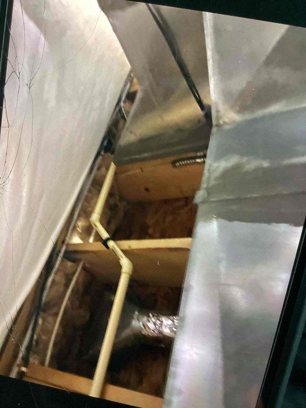Responded to customer complaint of water dripping and ceiling staining. Upon inspection, discovered excessive condensation forming on supply air duct in attic space. Customer had already opened drywall to expose affected ductwork. Inspected galvanized metal supply duct and elbow fittings in attic cavity, noting condensation accumulation on exterior duct surfaces. Photographed existing ductwork installation showing uninsulated metal ducts in contact with unconditioned attic air, which is causing temperature differential and resulting condensation issues. Assessed surrounding wooden framing and building materials for moisture damage. Provided customer with repair options to address condensation problem, including duct insulation upgrades and proper vapor barrier installation to prevent future moisture accumulation and ceiling damage.