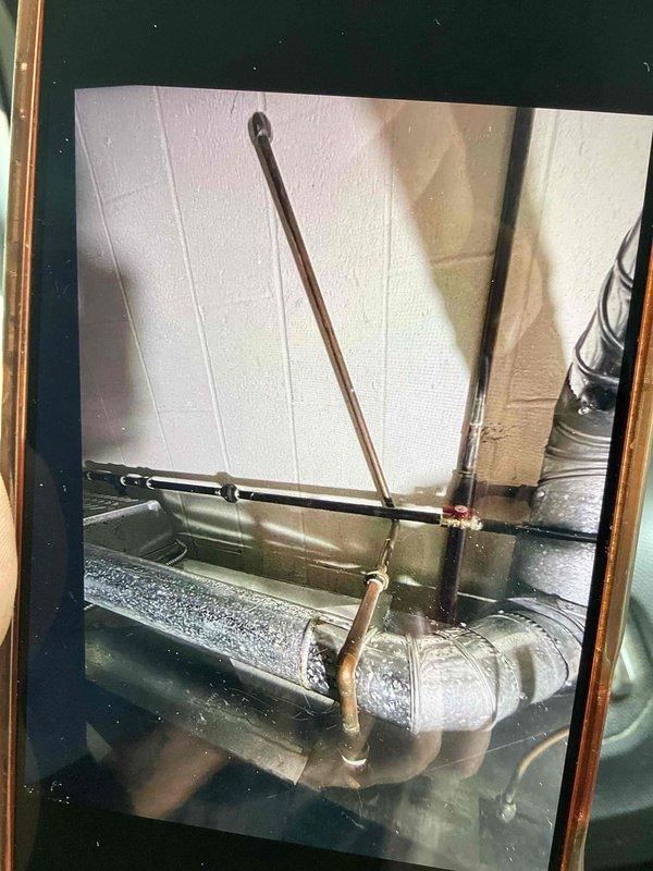Responded to report of water dripping from copper union on furnace in basement. Upon arrival, inspected furnace and adjacent hot water heater to identify source of moisture. Located condensate drainage issue at furnace drip pan with improper drainage through clear plastic elbow fitting. Verified copper refrigerant lines and mounting brackets were secure and properly installed. Addressed drainage concern to prevent future water accumulation in basement area.