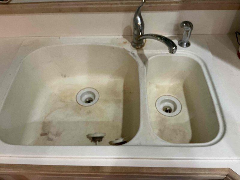 Completed full replacement of kitchen double-basin sink and laundry room sink, including installation of new faucets, shut-off valves, and drain tubular assemblies for both fixtures. Removed existing stained kitchen sink and outdated laundry sink fixtures, installed new units with updated plumbing connections, and verified proper drainage and water supply operation upon completion.