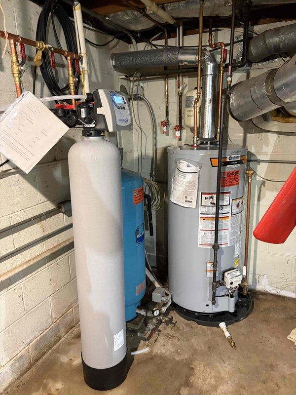 Removed existing Kinetico water softener system and completed installation of new iron filter and 40-gallon gas short water heater. All plumbing connections were made with copper piping, including proper hot and cold water lines with shutoff valves, temperature and pressure relief valve, and gas line connection. Blue pressure tank was positioned and connected to the filtration system. All units were properly vented, tested for leaks, and confirmed operational.