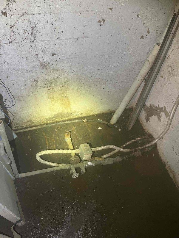 Responded to water emergency at rental property where pressure tank catastrophically failed, rupturing at the bottom and causing significant basement flooding. Upon arrival, found several inches of standing water throughout utility area with pressure tank showing severe corrosion and complete structural failure at base. Well pump system components were partially submerged in flood water. Documented extensive water damage to walls, floor, and surrounding infrastructure. Assessed condition of well pump and associated plumbing connections for water damage and functionality. Photographed failed pressure tank showing advanced deterioration, rust, and corrosion that led to catastrophic failure. Captured documentation of flooded conditions, submerged mechanical equipment including brass fittings and flexible conduit, and water intrusion affecting electrical panel area. Provided photographic evidence and detailed findings for property management review regarding necessary repairs and equipment