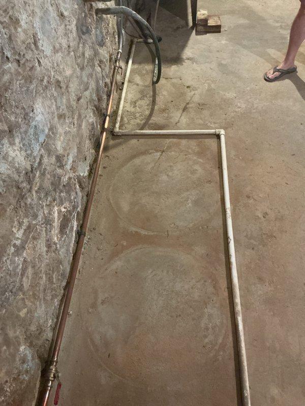 Completed backflow preventer installation in basement utility area with aging plumbing infrastructure. Standard backflow testing performed per code requirements, with vault testing assessment conducted onsite to ensure compliance with OSHA safety protocols due to confined space conditions and deteriorated foundation walls showing moisture infiltration. Documentation photos captured existing copper piping with oxidation and concrete surfaces displaying efflorescence for service records.