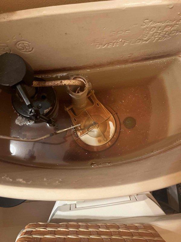 Completed prepaid club maintenance visit for plumbing inspection. Examined toilet tank interior, noting discolored water with sediment buildup and mineral deposits on porcelain surfaces and metal components. Documented condition of flush valve assembly, fill valve mechanism with float ball, and connecting hardware showing signs of age-related corrosion. Also inspected HVAC ductwork and insulation panels, observing deterioration at panel junction with accumulated debris at seam connection point.