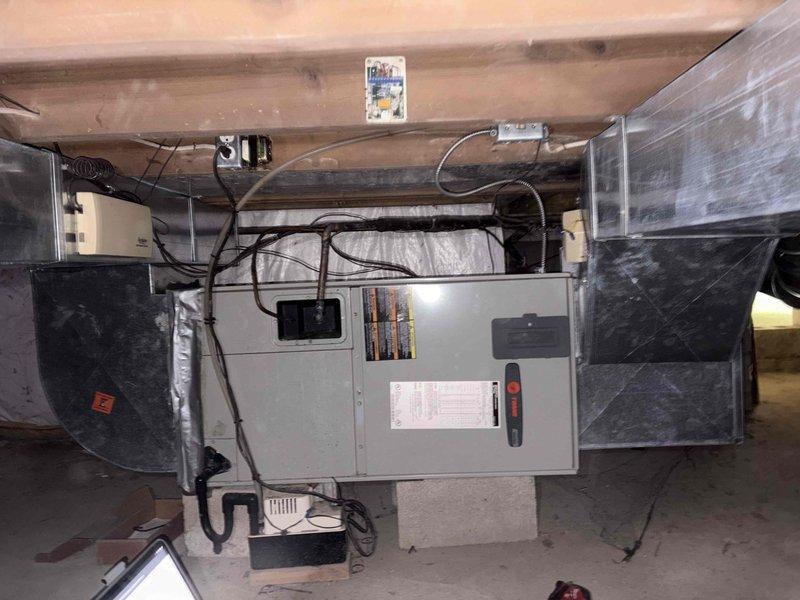 Responded to no cooling complaint on residential property with 2008 Trane air conditioning system. Upon arrival, evaluated 18-year-old outdoor condensing unit and indoor air handler located in basement mechanical room. Conducted comprehensive system assessment including electrical connections, refrigerant circuit components, and ductwork configuration. Due to age of equipment and nature of failure, provided detailed estimate for complete HVAC system replacement. Documented existing installation with photos showing current air handler placement on concrete block stand, existing flexible ductwork connections with reflective insulation, electrical disconnect and wiring configuration, and overall mechanical room layout for proper equipment sizing and replacement planning.