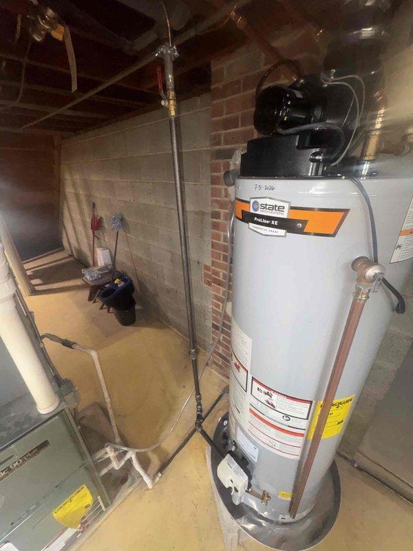 Completed water treatment system installation in residential basement utility area. New water treatment equipment was installed and integrated with existing plumbing infrastructure, including connections to the water heater and main water supply lines using copper piping and appropriate fittings to ensure proper water flow and treatment throughout the home.