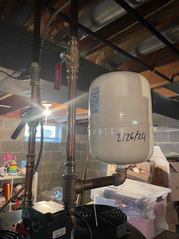 Responded to complaint of hot water tank depleting within five minutes of use throughout the residence. Upon arrival, inspected Kobella brand tanked water heater that was recently installed in February in basement mechanical room. Verified proper installation of expansion tank with date marking on unit surface, copper supply and discharge piping with brass fittings and shut-off valves, and all connections secure without visible leaks. Examined water heater control panel settings and EnergyGuide specifications to confirm unit capacity appropriate for household demand. Assessed plumbing configuration including flexible braided connectors and valve positioning. Determined potential issue with thermostat calibration or heating element performance causing premature hot water depletion. Documented equipment condition and installation quality through photographic records showing expansion tank, piping system, and water heater unit in unfinished basement setting. Recommended monitoring water t