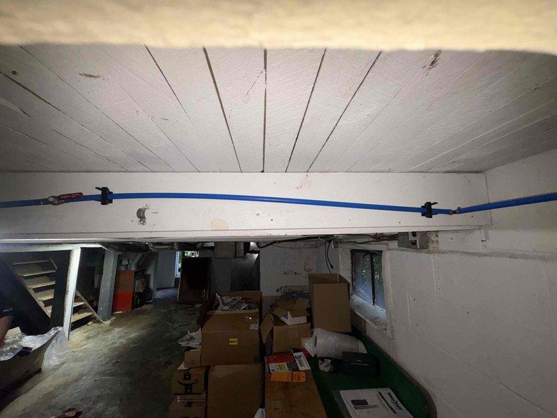 Returned to property to complete installation of jet pump, pressure tank, and chlorine injection system as previously recommended and sold. All materials were received and verified prior to installation. Customer approval was obtained through financing for the complete system replacement. Documented existing chlorine injection equipment showing 2 gallons per 15 bags of water dosing rate marked on storage tank. Photographed basement work area and utility space to record pre-installation conditions and equipment access points for the upcoming replacement work.