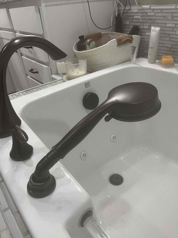 Responded to service call for broken handheld showerhead in master bathroom tub. Removed damaged unit and installed customer-supplied replacement handheld showerhead with flexible metal hose, connecting it to existing tub faucet fixture with oil-rubbed bronze finish. Tested water flow and spray patterns to ensure proper operation and verified secure connections with no leaks.
