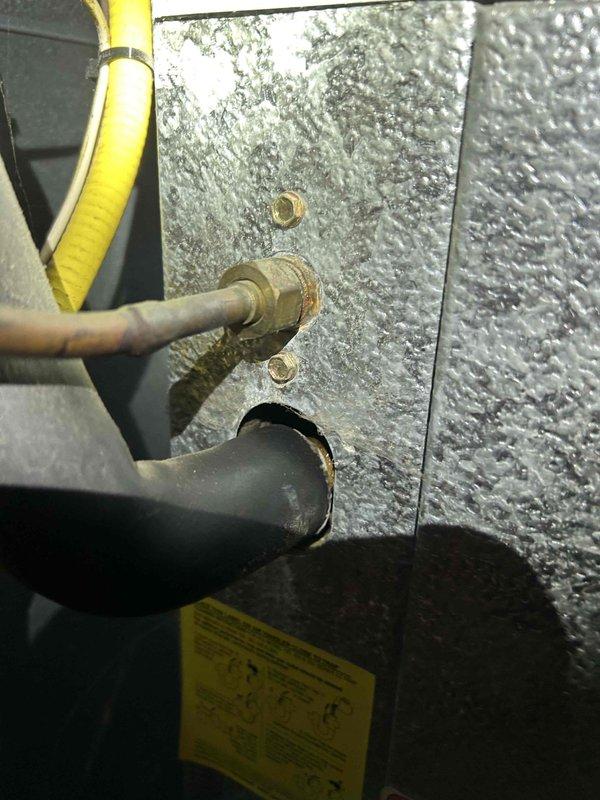 Completed cooling maintenance club visit on air handler system. Upon inspection, found evaporator coil with heavy dirt and mold accumulation on fins, requiring attention. Noted significant oxidation and corrosion on copper refrigerant lines with greenish-brown patina and rust staining. Observed rust formation and debris buildup on unit housing and frame. Documented condition of refrigerant line connections and insulated suction line passing through metal panel. System shows signs of extended operational use with maintenance needs identified for future service recommendations.