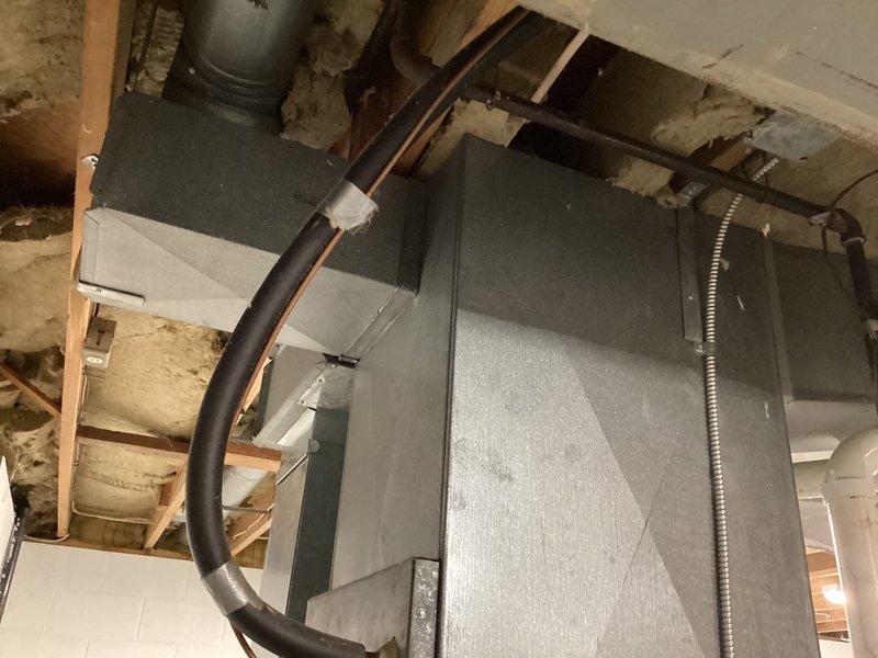 Performed comprehensive HVAC estimate for air conditioning system replacement in residential property with multiple units including in-law suite. Evaluated existing 1992 AC unit located in basement mechanical room, noting system age exceeding typical service life expectancy. Assessed current installation configuration including air handler unit, ductwork connections with black flexible ducts and metallic flexible ducting, and integration with existing electrical panels and utility infrastructure. Documented equipment location, access points, and surrounding mechanical systems to determine replacement specifications and installation requirements for new system.