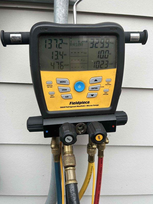 # HVAC Service Report

Responded to no cooling complaint for intake room system. Upon arrival, performed diagnostic testing on multi-unit residential HVAC installation consisting of three condenser units positioned on concrete pads. Connected Fieldpiece SMAN refrigerant manifold and micron gauge to affected unit to measure system pressures and temperatures. 

Diagnostic readings indicated abnormal pressure differential with high-side pressure measuring 312 psig and discharge temperature at 134°F, while low-side pressure registered 323 psig at 100°F. These readings confirmed refrigerant system imbalance affecting cooling capacity. Performed complete system evaluation including electrical disconnect verification, refrigerant charge analysis, and compressor operation assessment to restore proper cooling function to intake room.