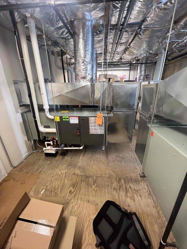 Responded to service call for non-operational cooling system in commercial intake room. Upon inspection, assessed existing HVAC unit and ductwork configuration in mechanical space. Documented equipment conditions and system layout, including gray metal air handler unit, metallic flexible ductwork, rigid metal supply/return ducts, and associated PVC drainage piping. Provided comprehensive estimate for complete system replacement to restore cooling capacity to the intake room area.