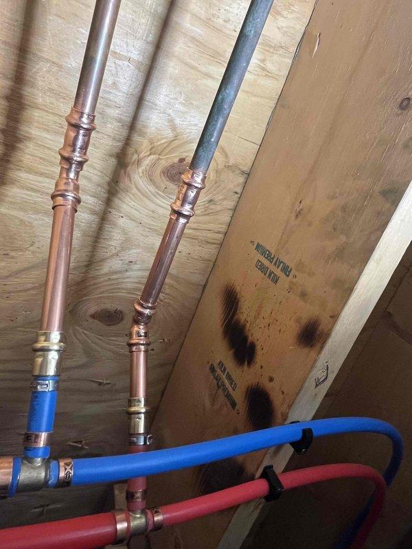 Completed spot repairs and hose bib replacement at residential property. Installed new exterior hose spigot with chrome-plated body and green plastic valve handle, properly mounting unit to brick exterior wall. Performed attic plumbing repairs including copper pipe connections with compression fittings and secured flexible PEX lines (red and blue) to wooden joists using appropriate fasteners. All work completed with assistant over four-hour service period, ensuring proper water flow and leak-free connections throughout the system.