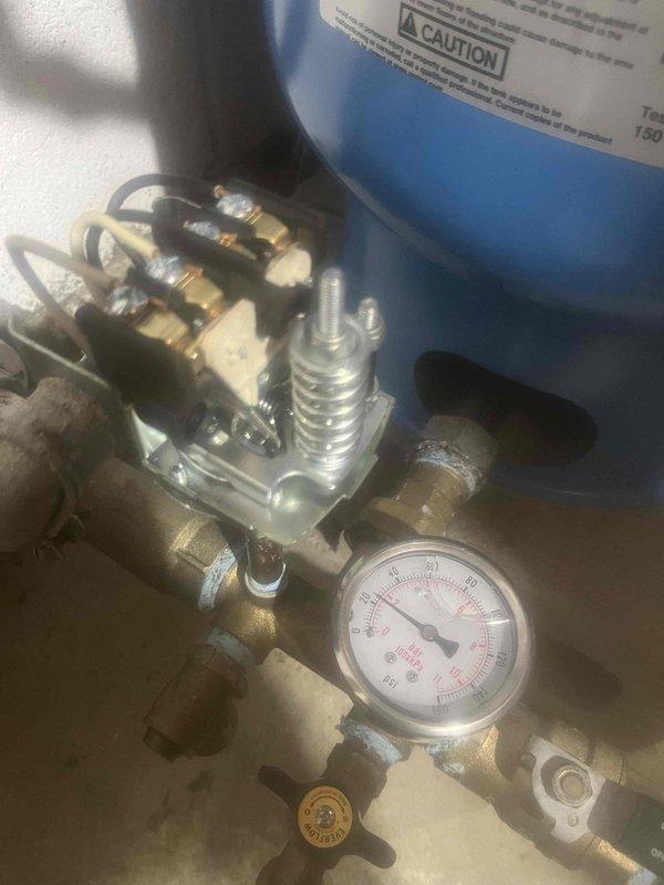 Responded to low water pressure complaint and performed diagnostic inspection of residential water system. Kinetico water treatment company had previously inspected their equipment and determined the issue originated from the well pump system. Conducted electrical testing of well pump circuit using digital clamp meter, which showed a reading of 98 amps, indicating potential pump motor issues. Inspected pressure tank assembly and associated components, including pressure gauge, pressure switch, and piping connections. Pressure gauge readings and visible condition of brass fittings and valve assembly were documented. Findings support determination that well pump is the source of the low pressure condition and will require further service or replacement by well pump specialist.