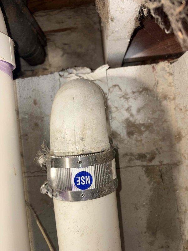 Responded to water leak in basement bathroom area. Upon inspection, identified active leak at PVC to copper pipe transition point. The copper piping system showed significant age-related deterioration with green patina oxidation and corrosion present throughout multiple sections. Leak was isolated to the coupling joint where white PVC pipe connects to copper supply line. Repaired transition connection using appropriate coupling hardware and secured with metal clamp. Verified repair integrity and confirmed no additional leaks present in surrounding plumbing system.