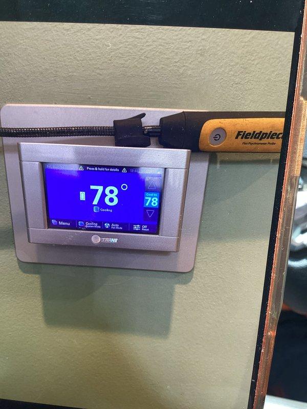 Responded to callback for thermostat calibration issue following recent maintenance visit. Upon arrival, verified thermostat display reading 78-79°F while occupants reported uncomfortably cold conditions. Used Fieldpiece temperature probe to measure actual room temperature and confirmed significant discrepancy between thermostat reading and ambient conditions. Checked supply air temperature at 55.1°F with 84.7% relative humidity, confirming system was overcooling space due to inaccurate thermostat sensing. Recalibrated thermostat temperature sensor to match actual room conditions and verified proper system cycling.