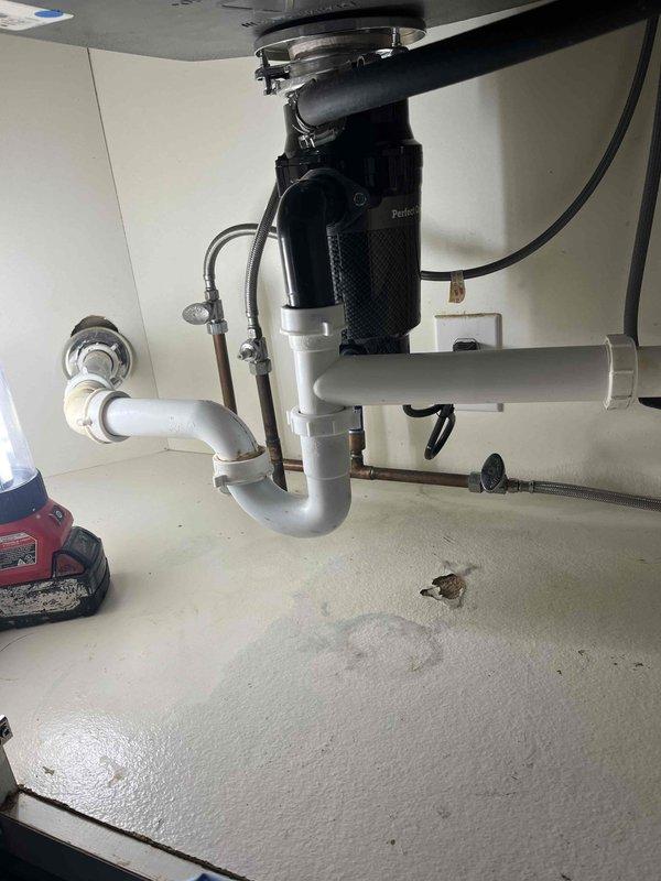 Responded to service call for garbage disposal replacement. Presented customer with multiple disposal unit options and completed installation of new black residential garbage disposal unit under kitchen sink. Connected disposal to existing white PVC P-trap drain configuration and verified proper mounting to sink drain assembly. Applied membership discount to service as requested.