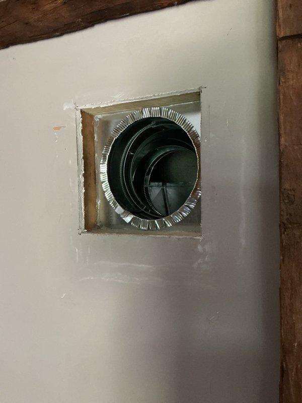 Completed installation of return air register and associated ductwork in residential ceiling and wall locations. Installed flexible metallic duct with proper boot connection through ceiling opening, ensuring secure attachment and proper sealing at termination point. Mounted white return air grille on interior wall with horizontal slat design, integrated with existing structural timber framing elements. All components installed to code specifications with attention to proper airflow and system integration.