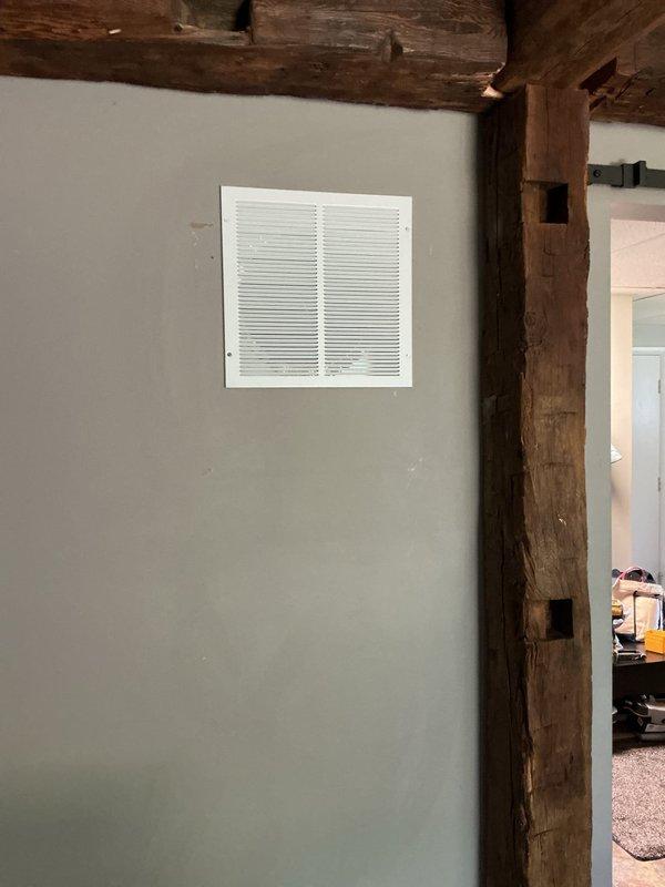 Completed installation of return air register and associated ductwork in residential ceiling and wall locations. Installed flexible metallic duct with proper boot connection through ceiling opening, ensuring secure attachment and proper sealing at termination point. Mounted white return air grille on interior wall with horizontal slat design, integrated with existing structural timber framing elements. All components installed to code specifications with attention to proper airflow and system integration.