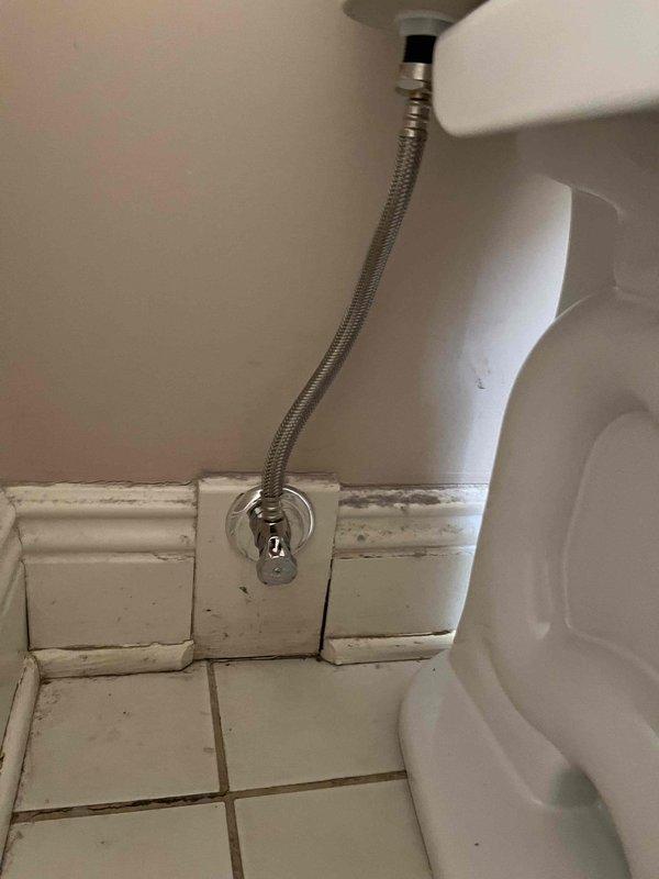 Completed toilet replacement in bathroom, removing old two-piece unit and installing new white porcelain toilet with updated braided metal supply line and chrome shut-off valve. Replaced 13 shut-off valves throughout the property, including installation of chrome angle stops for bathroom fixtures serving the bathtub and shower assembly with wall-mounted faucet handles and tub spout.