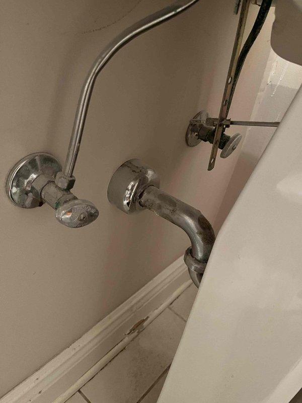 Completed toilet replacement in bathroom, removing old two-piece unit and installing new white porcelain toilet with updated braided metal supply line and chrome shut-off valve. Replaced 13 shut-off valves throughout the property, including installation of chrome angle stops for bathroom fixtures serving the bathtub and shower assembly with wall-mounted faucet handles and tub spout.