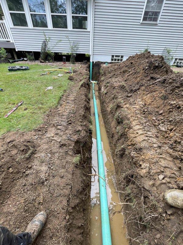 Excavated and installed new downspout discharge line and cleanout assembly. Dug trench from foundation to discharge point, installed PVC drainage pipe with proper slope for water flow, and set cleanout access point for future maintenance. Backfilled excavation and restored work area upon completion.