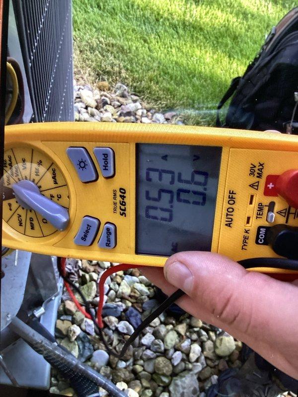 Performed routine cooling maintenance member visit to address reported AC leak at air handler. Inspected condensate drain system and found evidence of moisture accumulation beneath unit, with visible corrosion on drain piping components. Verified proper drainage function and measured system voltage at outdoor condenser unit, recording 65.9 volts during diagnostic testing. Documented plumbing connections and electrical readings with photos for service records.