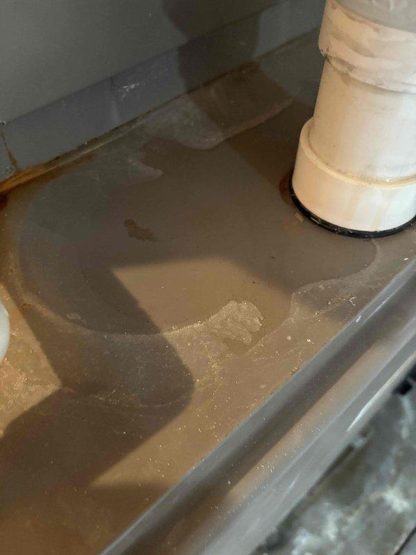 Responded to service call for slow-draining upstairs bathtub and water accumulation near AC unit. Upon arrival, discovered significant flooding in basement utility area with several inches of standing water covering concrete floor. Inspected plumbing infrastructure including vertical PVC drain lines and identified water intrusion issue affecting mechanical room housing water heater and HVAC equipment. Customer had previously attempted to clear tub drain with snake without success. Assessed drainage system, located source of water backup, and cleared blockage in main drain line. Verified proper drainage flow restored to upstairs bathtub fixture and addressed water accumulation issue in basement area near air handler unit.