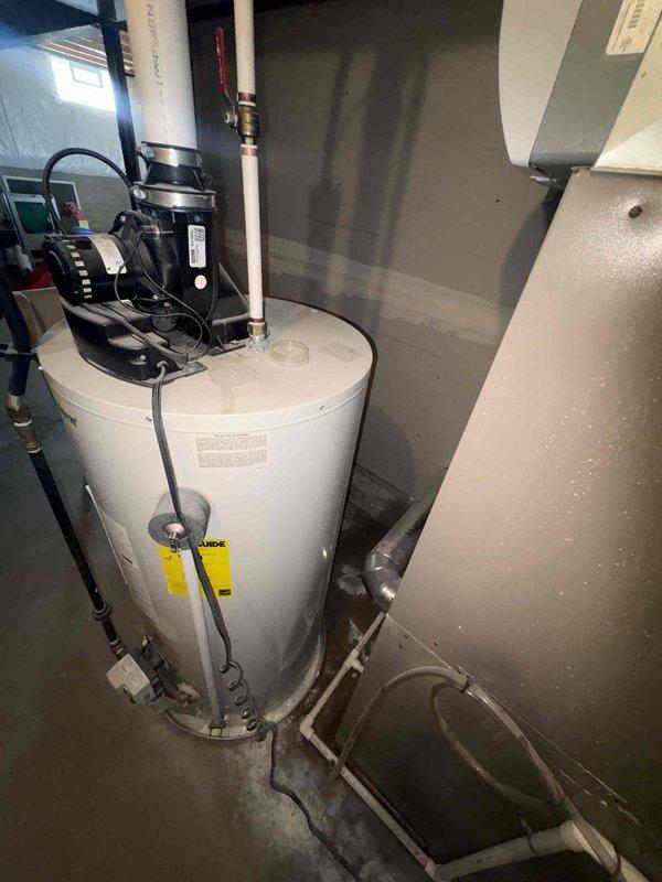 Responded to service call for slow-draining upstairs bathtub and water accumulation near AC unit. Upon arrival, discovered significant flooding in basement utility area with several inches of standing water covering concrete floor. Inspected plumbing infrastructure including vertical PVC drain lines and identified water intrusion issue affecting mechanical room housing water heater and HVAC equipment. Customer had previously attempted to clear tub drain with snake without success. Assessed drainage system, located source of water backup, and cleared blockage in main drain line. Verified proper drainage flow restored to upstairs bathtub fixture and addressed water accumulation issue in basement area near air handler unit.