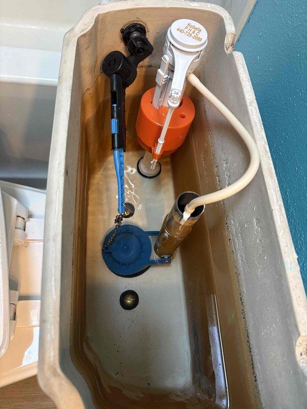 Responded to a toilet leak complaint and performed diagnostic inspection. Upon examination, removed tank lid and identified worn flapper seal as the source of water leakage. Inspected all tank components including fill valve, flush valve assembly, and flapper mechanism. Noted normal mineral deposits and age-related wear consistent with standard use. Documented existing conditions with photographs for service records.